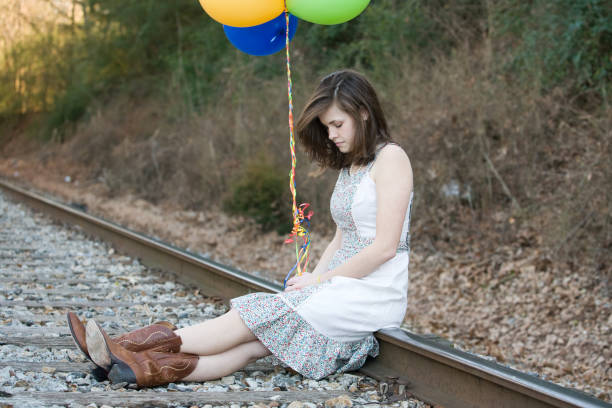 young woman on railroad tracks holding balloons