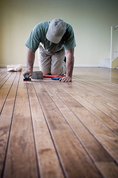Worker putting finishing details on hardwood flooring stock photo