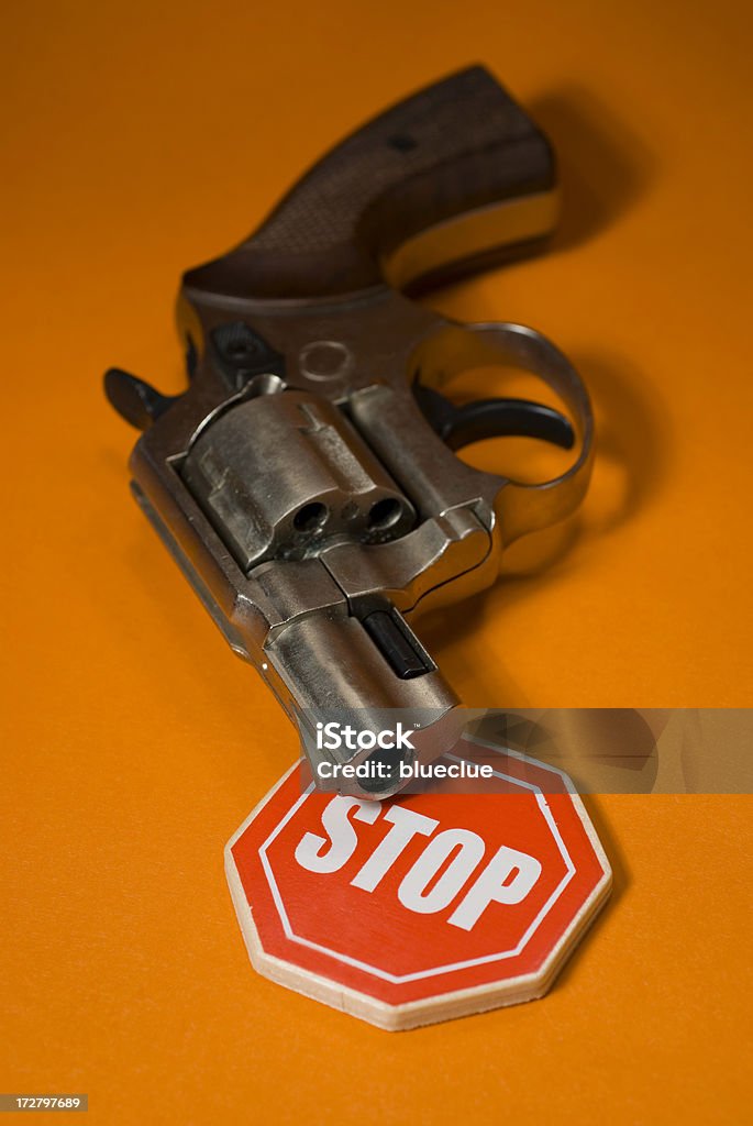 Stop gun violence Against the gun violence concept. gun and stop sign with orange background Adversity Stock Photo