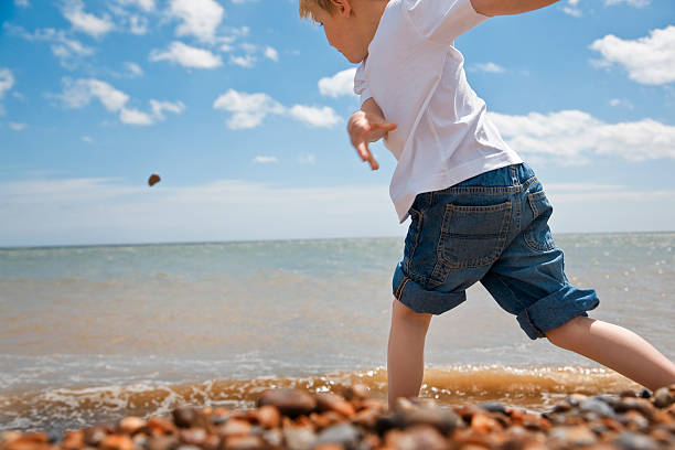 zabawa na plaży na wspaniały dzień - throwing stone little boys child zdjęcia i obrazy z banku zdjęć