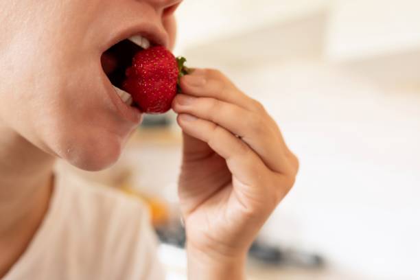 istock woman bites strawberry during snack. proper nutrition 1727986429