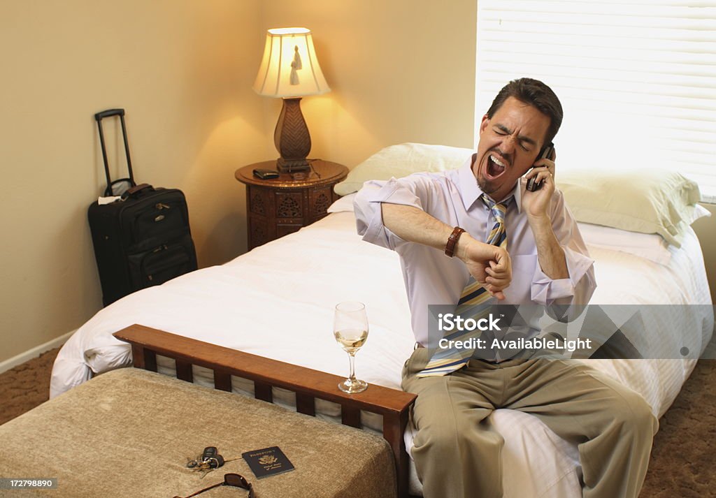 Business Traveler on Phone Yawning I guess I do have time for that drink before the meeting, but now I'm tired! Hotel Room Stock Photo