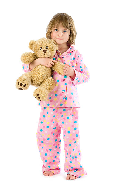 Little girl wearing pyjamas holding teddy on white stock photo