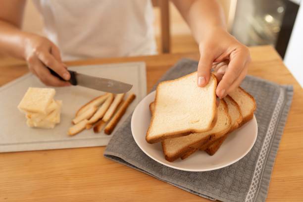 istock women's hands slicing bread with a knife on a board 1727993602