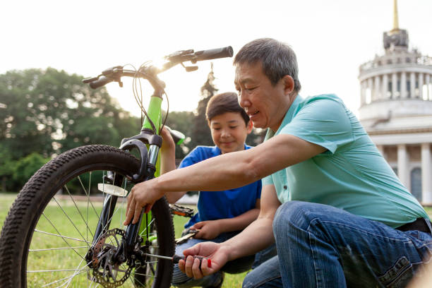 asian father helping son to repair bike with tools, korean little boy watching dad fix broken bike - ten speed bicycle imagens e fotografias de stock