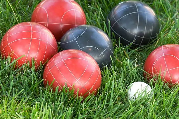 Black and red bocce balls nestled in lush green grass.