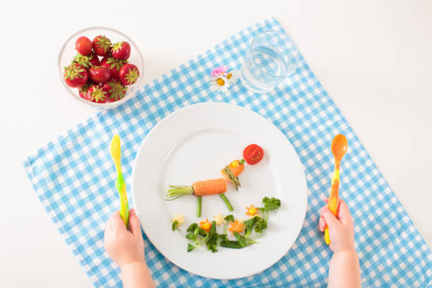 Healthy vegetable meal for young child. Nutrition for baby and toddler. Funny decorated animals made of veggies for kids. Solid food for infant. Carrot, broccoli, corn and greens for children.