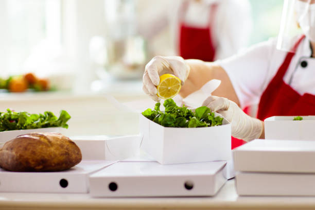 Food takeaway in restaurant. Cafe staff cooking takeout order. Safety and hygiene for food home delivery. Chef with salad in cardboard container, eco friendly, vegan. Meal fresh ingredient kit.