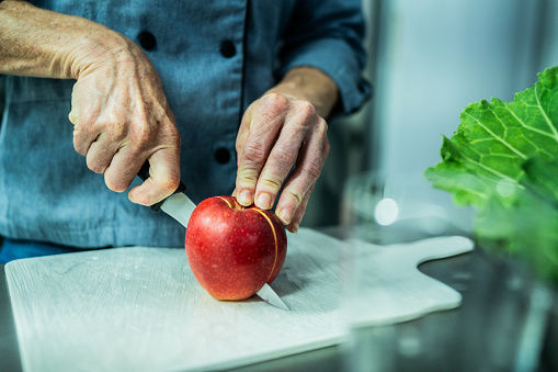 Close-up of a chef cutting an apple in commercial kitchen