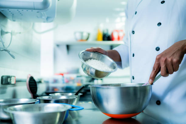 istock Chef pouring ingredients into a mixing bowl at commercial kitchen 1728016018
