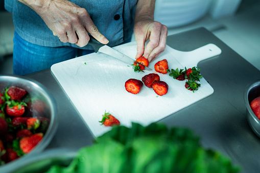Chef cutting strawberry at commercial kitchen