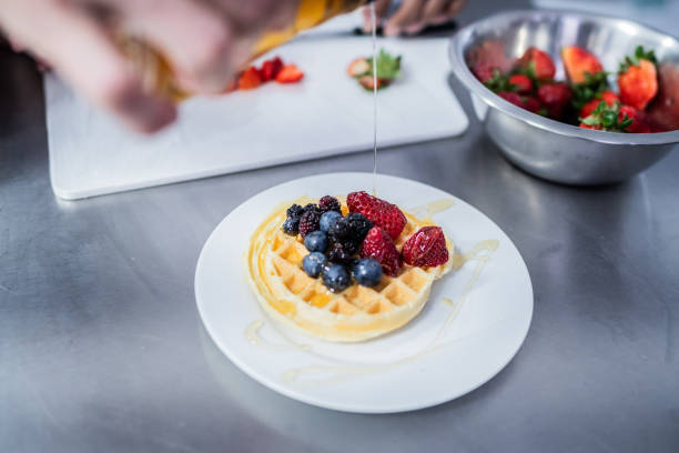 Close-up pf a chef pouring honey on waffle at commercial kitchen