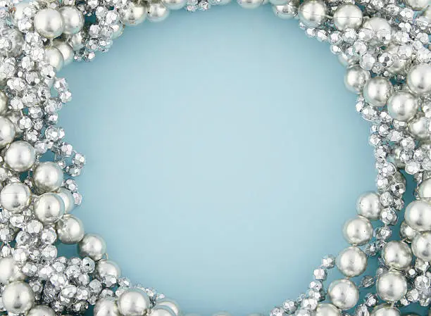 Silver beads on a light blue background. Space for text in the center.