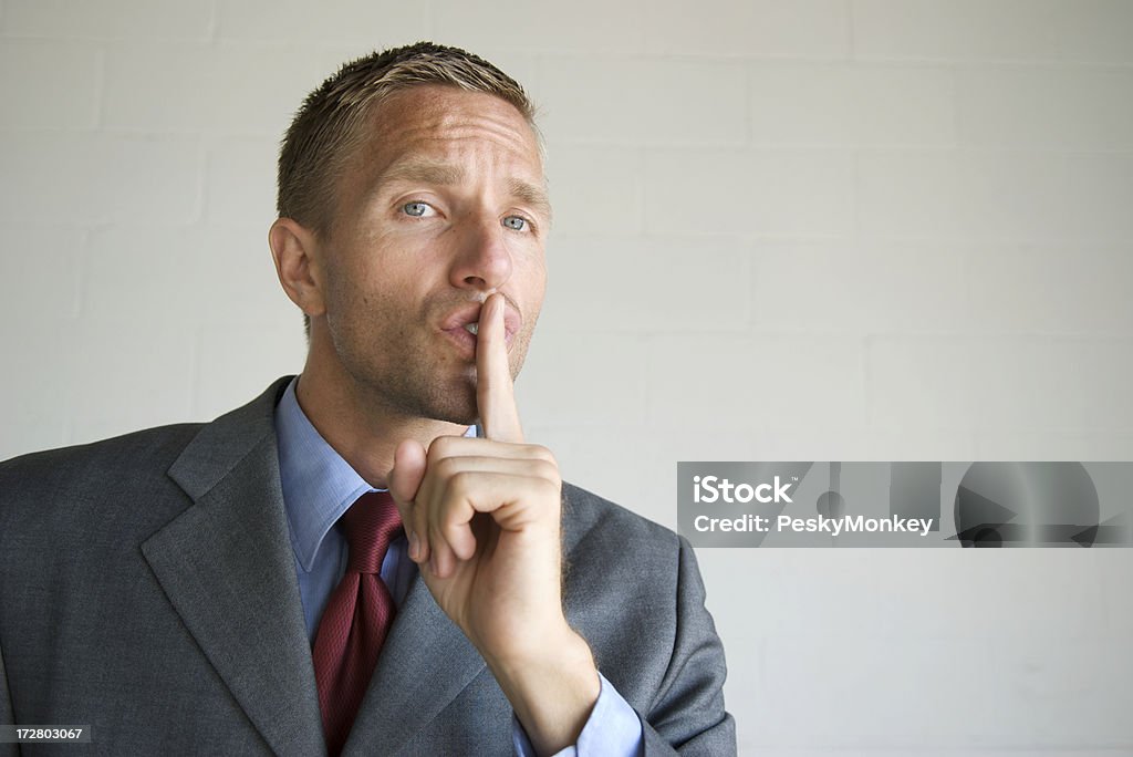 Shhh. Empresario sostiene dedo en los labios - Foto de stock de Dedo sobre labios libre de derechos