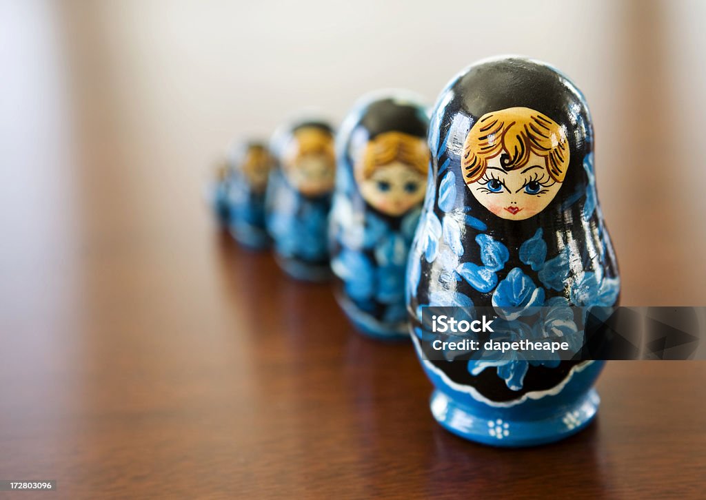 Matryoshka doll Russian style Matryoshka dolls that stand side by side on a wooden surface.  Dolls designed to pull in half and fit perfectly inside the larger. Russian Nesting Doll Stock Photo