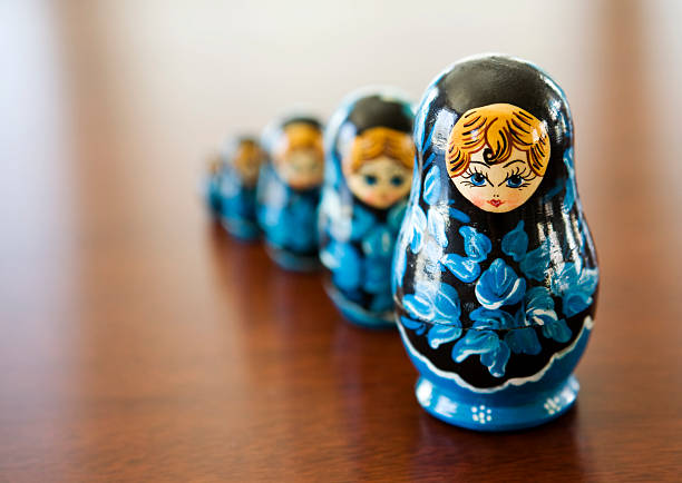 Matryoshka doll Russian style Matryoshka dolls that stand side by side on a wooden surface.  Dolls designed to pull in half and fit perfectly inside the larger. matrioska stock pictures, royalty-free photos & images