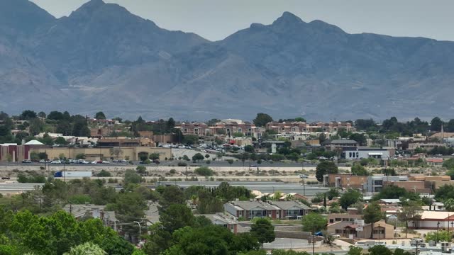 Houses and homes in neighborhood in Southwest USA shadowed by tall mountain range in desert.