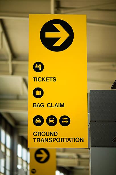 Airport Sign "Yellow sign at Austin Bergstrom International Airport indicating the direction toward the ticket counter, baggage claim and ground transportation." austin airport stock pictures, royalty-free photos & images