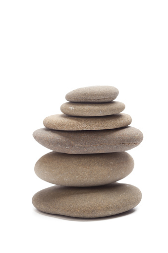 Balancing of pebbles over white background.