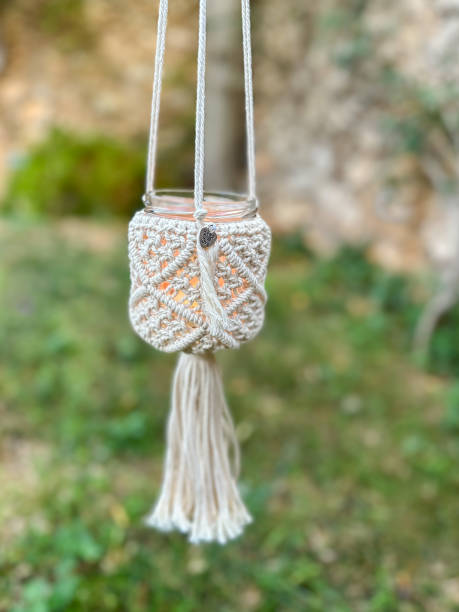 istock Handmade macrame glass jar with lit candle hanging on patio 1728038968