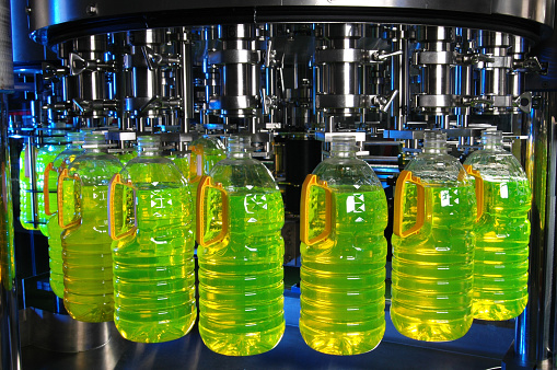 Factory machine producing and filling bottles with liquid (with blue highlights).