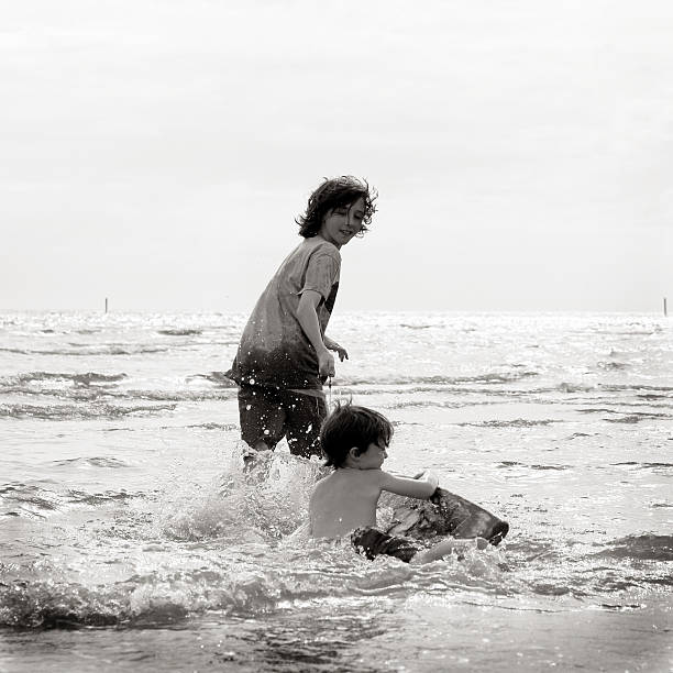 hermanos jugando en la playa - parker brothers fotografías e imágenes de stock