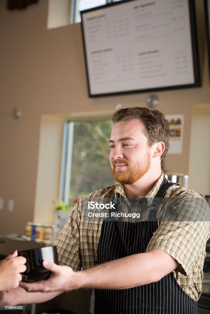 Young People in a Cafe A server in a cafe handing drinks to customers. 20-29 Years Stock Photo