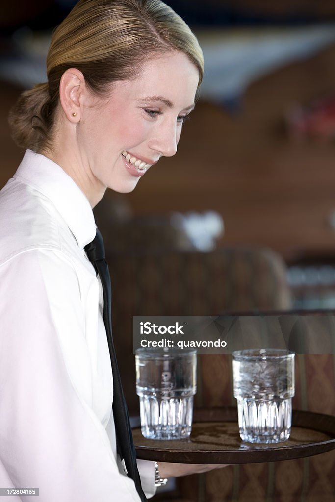 Красивая блондинка в ресторане официантка, где воды очки, улыбается - Стоковые фото Официантка роялти-фри