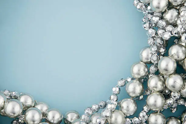 Silver beads on a light blue background with space for text.