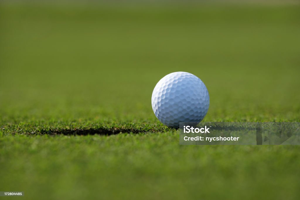 Golf Ball next to hole Close up of Golf ball next to hole on putting green. Golf Stock Photo