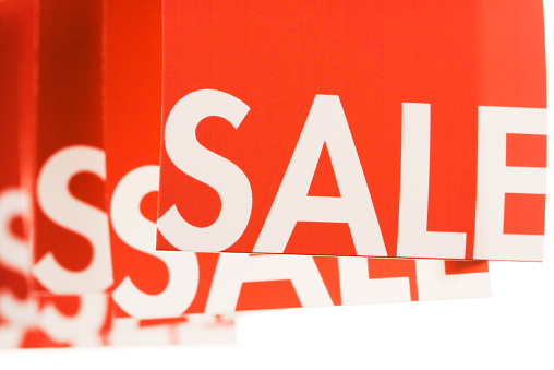 Hanging row of red sale paper price tags, advertising and marketing labels, store signs for retail shopping promotion, on a white background.