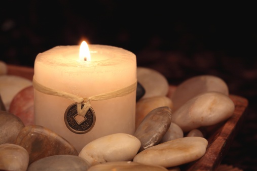 Burning candle with metal disk that has oriental symbols. click below for other candle images.