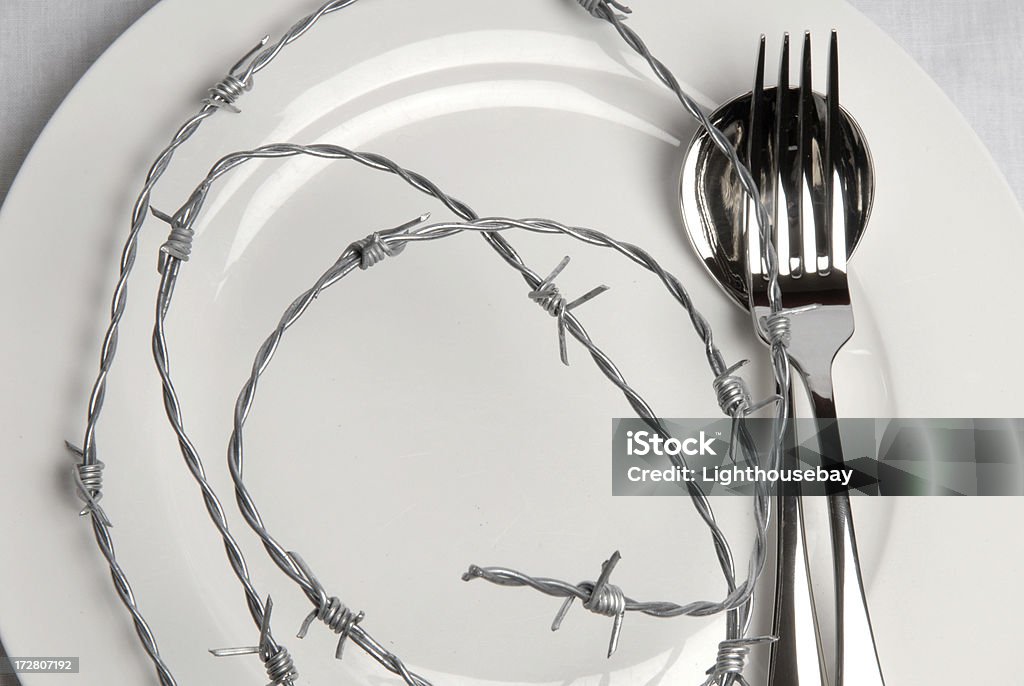 Plaque blanche recouverts de fil barbelé-Régime amaigrissant métaphore - Photo de Alimentation lourde libre de droits