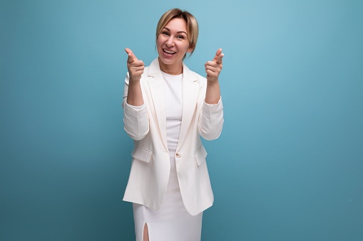 young confident pretty slim blond boss woman in an elegant jacket and dress on a blue background with copy space.