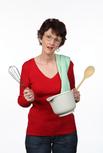 Attractive old-timey housewife in apron holding a wooden spoon
