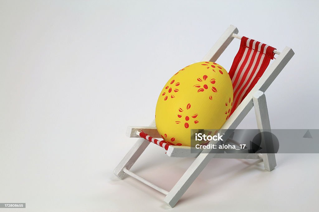 Easter holidays A self painted Easter egg on a deckchair with a white background. Easter vacation. Space for text. Animal Egg Stock Photo