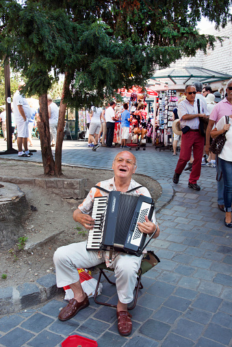 A street musician sings and plays accordion in an open area selling souvenirs in Budapest, Hungary.