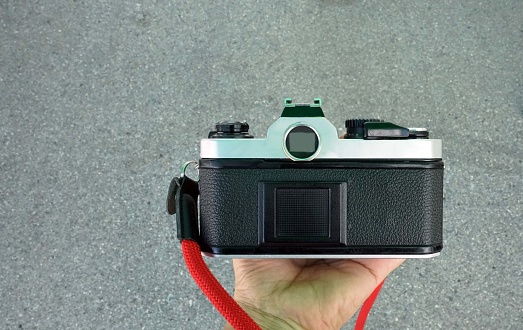 An old film camera in hand isolated on on road surface background, retro vintage concepts.