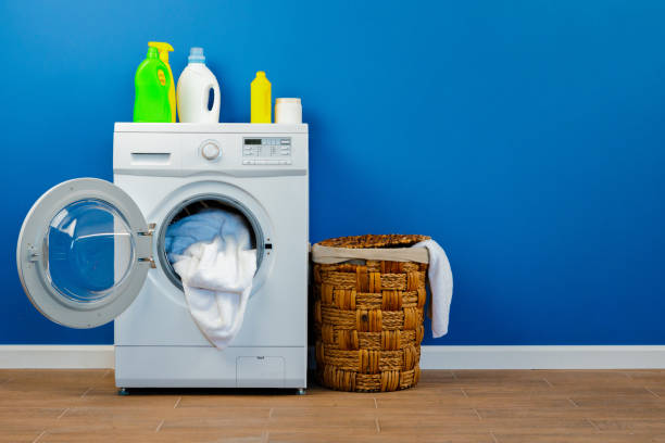 istock Washing machine with laundry on blue wall background 1728119631