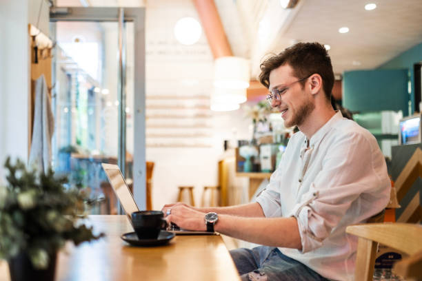 istock Young Man Dives into Work with his Laptop at a Cozy Cafe 1728121258