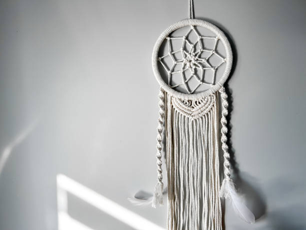 istock Handmade cotton macrame Dreamcatcher on a gray wall background. Traditional amulet to protect sleep. Home decor made from lace on the wall. Women's hobby. 1728125554