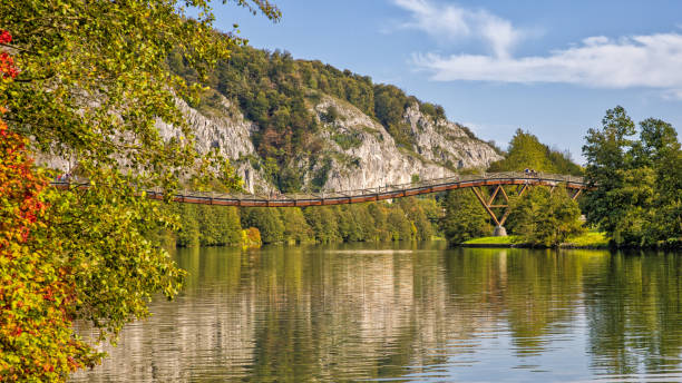 die berühmte fußgänger-holzbrücke tatzlwurm über den rhein-main-donau-kanal mit wanderern im sonnenlicht und herbstlichen bäumen - essing stock-fotos und bilder