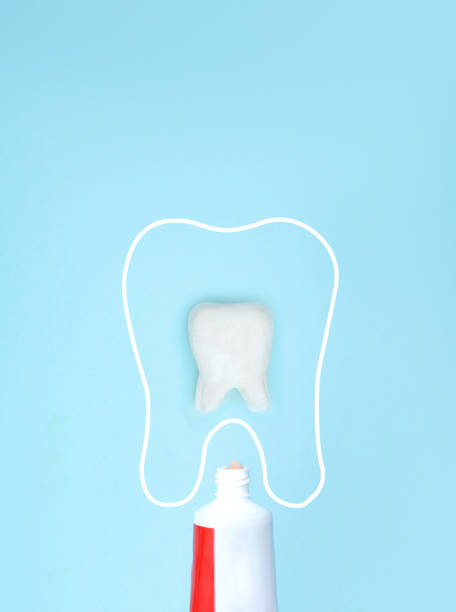 istock Small Red Toothpaste Tube with open lid, white molar tooth model and thin linear molar tooth on blue background. Tooth symbol sign. Means to care for the oral cavity. 1728135551