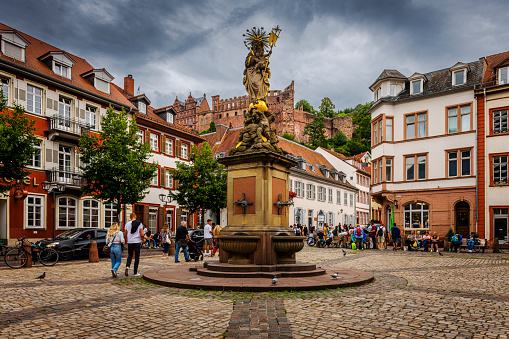Heidelberg, Germany - August 26, 2023:  Many people in the pedestrian zone at Kornmarkt with Mariensäule Fountain at famous city Heidelberg in Germany