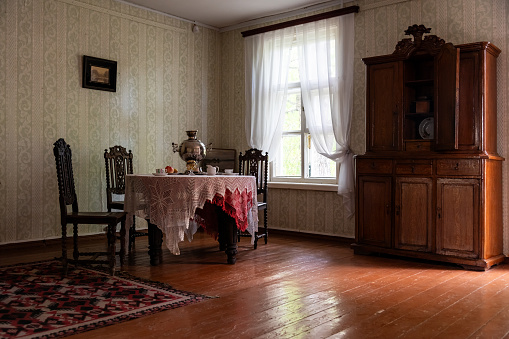 Original interior of a dining room in a rural house with a buffet, a table with a tablecloth and a samovar.