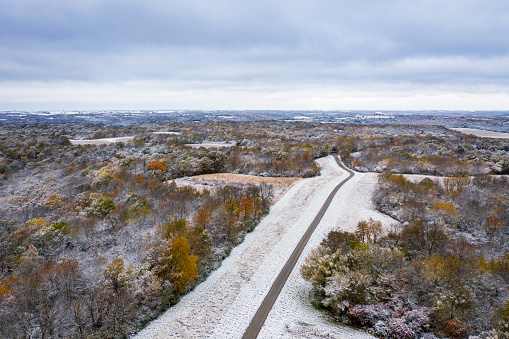 Gravel road, forest and harvested corn field dusted by early snow, aerial view of Honey Creek Conservation Area in western Missouri