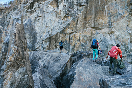 Climbers preparing for ascent. Three male female persons walking on the rocks. Extreme outdoor sport.