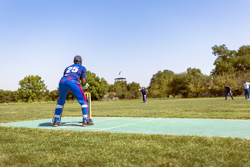 Cricket game. Wicket keeper preparing for stroke.