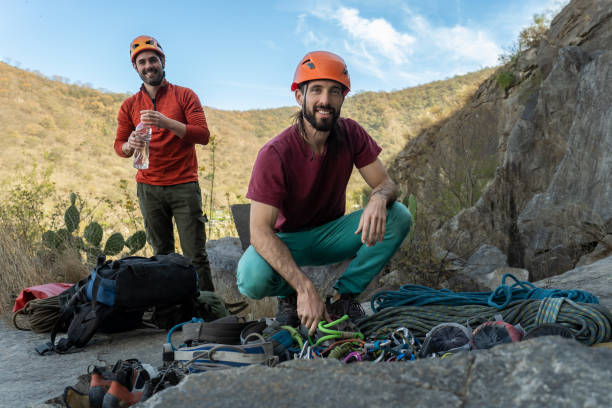 Smiling men preparing climbing gear. A bundle of rock climbing equipment.