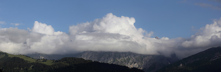 panoramic view of an alpine landscape with mountain peaks obscured by clouds